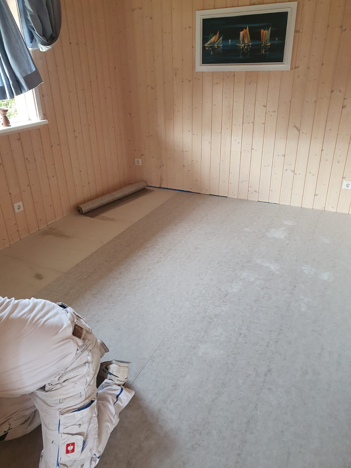 Beginn der Bodenverlegung in einem holzverkleideten Raum