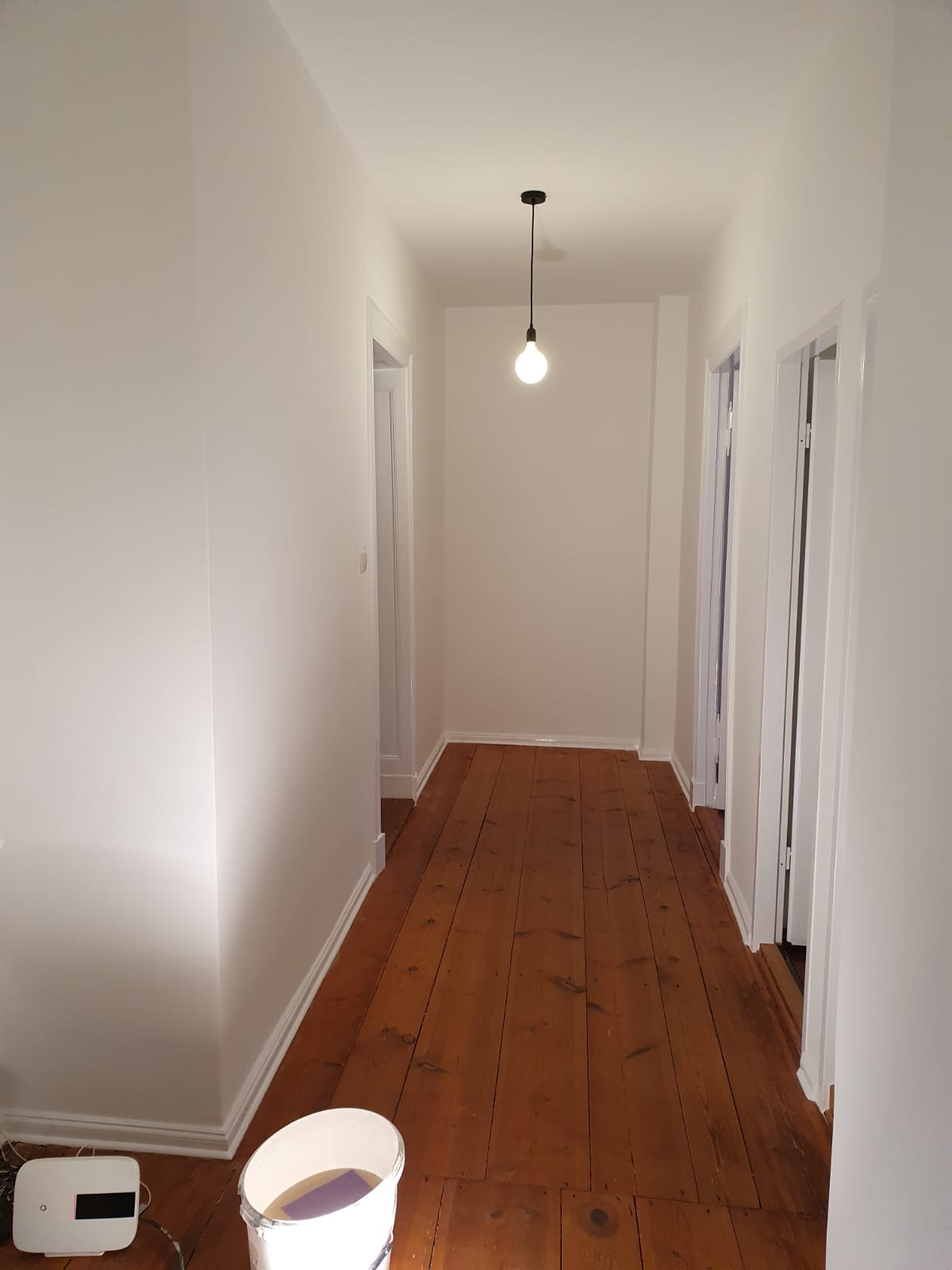 Fertig sanierter weißer Altbauflur mit Holzdielen