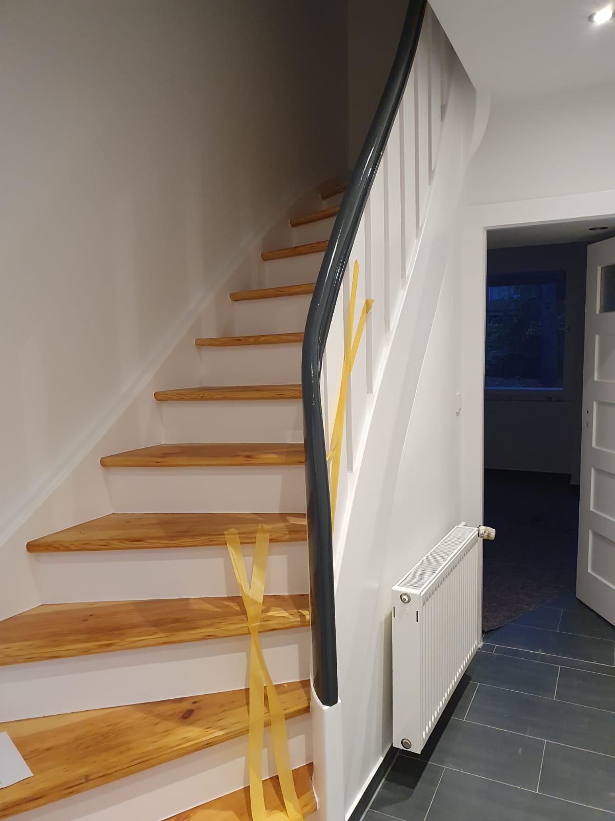 Fertig sanierte Holztreppe mit weißen Setzstufen und dunklem Handlauf